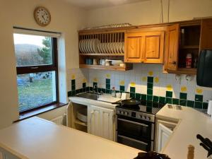 eine Küche mit einem Herd, einem Waschbecken und einem Fenster in der Unterkunft Glynsk Pier Cottage in Carna