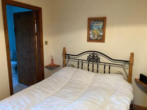 a bedroom with a white bed and a picture on the wall at Glynsk Pier Cottage in Carna