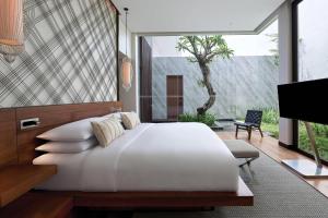 a bedroom with a large white bed and a tv at Renaissance Bali Uluwatu Resort & Spa in Uluwatu