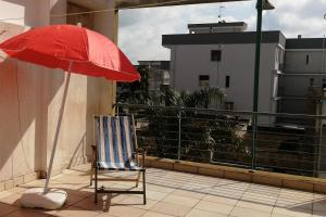 uma cadeira e um guarda-sol vermelho numa varanda em A casa di Rita em Surbo