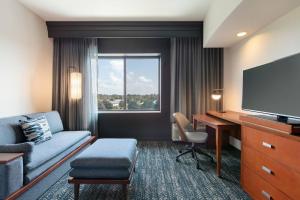 a hotel room with a couch and a desk and a television at Courtyard Lancaster in Lancaster