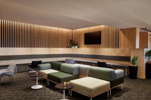 a lobby with a couch and a tv on a wall at Courtyard by Marriott Sydney-North Ryde in Sydney