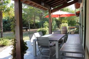 eine Terrasse mit einem Tisch, Stühlen und einem Sonnenschirm in der Unterkunft Les sittelles in Gaillac