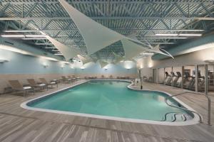 a pool in a large room with chairs and tables at TownePlace Suites by Marriott Oshawa in Oshawa