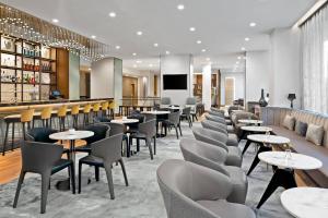 un restaurante con mesas y sillas y un bar en AC Hotel by Marriott Saint-Julien-en-Genevois, en Saint-Julien-en-Genevois