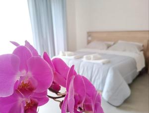 1 dormitorio con 1 cama con flores púrpuras en el primer plano en Civico 72, en Martano