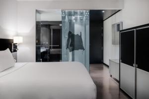 ムルシアにあるAC Hotel Murcia by Marriottの白いベッドとガラスの壁が備わるベッドルーム1室が備わります。