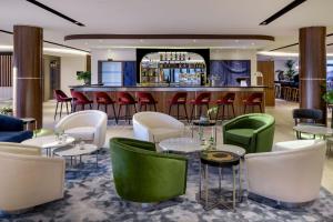 a restaurant with green and white chairs and a bar at AC Hotel by Marriott Saint-Julien-en-Genevois in Saint-Julien-en-Genevois