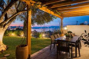patio ze stołem i krzesłami pod pergolą w obiekcie Myronis Villa Corfu Town w Korfu