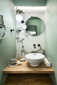 ein Badezimmer mit einem weißen Waschbecken und einem Spiegel in der Unterkunft Athens Luxury Rooms I in Athen