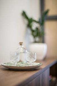 zwei Gläser auf einem Teller mit einer Flasche auf dem Tisch in der Unterkunft Athens Luxury Rooms I in Athen