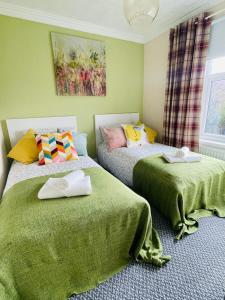 two beds in a room with green walls at Sheffield house on the hill in Manor
