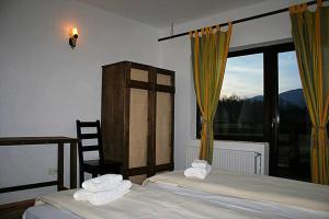 a bedroom with two beds and a large window at Taverna Pietrei Craiului in Zărneşti