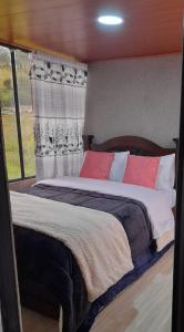 a bedroom with a large bed with colorful pillows at Glamping y Cabañas el Encanto-Girasoles in Tota