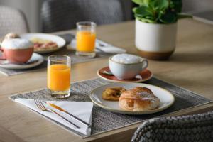 a table with plates of breakfast foods and orange juice at AC Hotel Ciutat de Palma by Marriott in Palma de Mallorca