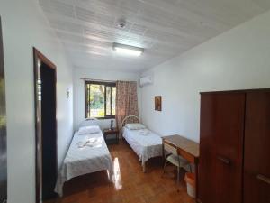 een kamer met 2 bedden, een tafel en een bureau bij Casa Santa Cruz in Passo Fundo
