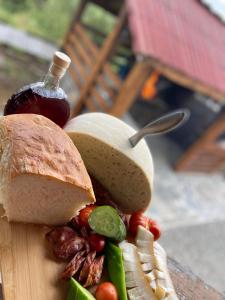 a cutting board with a sandwich and vegetables on it at Casa din Deal in Văleni