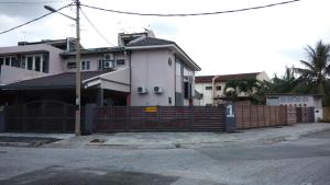 a house with a wooden fence in front of a street at Bercham Vacation House in Ipoh