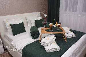 a white bed with a table with a glass of wine at VESTA Apartman in Sremska Mitrovica