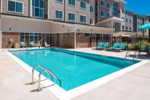 Residence Inn by Marriott Decatur في ديكاتور: مسبح وكراسي زرقاء ومبنى