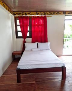 a bed in a room with a red curtain at Wikungo Hotel in Puerto Nariño