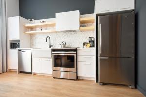 a kitchen with a stainless steel refrigerator and white cabinets at Les Lofts Charest - Par Les Lofts Vieux-Québec in Quebec City