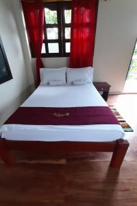 1 dormitorio con 1 cama grande y cortinas rojas en Wikungo Hotel, en Puerto Nariño