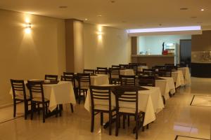 une salle à manger avec des tables et des chaises blanches dans l'établissement Hotel Portobello, à Aparecida