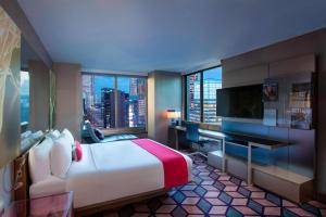 a hotel room with a bed and a desk with a monitor at W New York - Times Square in New York