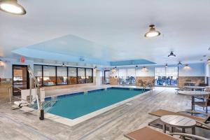TownePlace Suites by Marriott Bridgewater Branchburg في Branchburg Park: حمام سباحة في غرفة كبيرة مع طاولات وكراسي