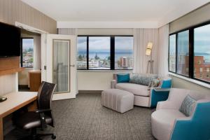 a hotel room with a desk and chairs and windows at Courtyard by Marriott Seattle Everett Downtown in Everett