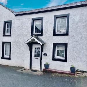 a white house with black windows and a door at Mews Cottage in Appleby