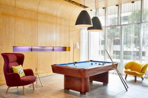 a room with a pool table and two chairs at Aloft Austin at The Domain in Austin