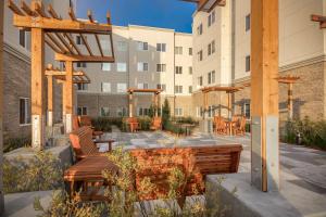 eine Terrasse mit Holzbänken und Tischen vor einem Gebäude in der Unterkunft Residence Inn by Marriott San Jose North/Silicon Valley in San Jose