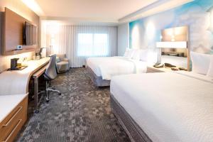 a hotel room with two beds and a desk at Courtyard by Marriott St. Augustine Beach in Saint Augustine Beach