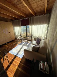 a living room with a couch and a large window at LA CASETTA NEI COLLI in Bergamo