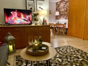 FeWo Fuchs Saig في لينزكيرش: غرفة معيشة مع طاولة مع كؤوس للنبيذ وتلفزيون