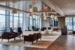 a lobby with couches and chairs and windows at AC Hotel by Marriott Cleveland Beachwood in Beachwood