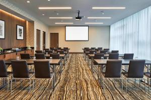 una sala de conferencias con mesas, sillas y una pantalla en AC Hotel by Marriott Cleveland Beachwood, en Beachwood