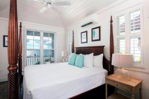 a bedroom with a bed with white sheets and blue pillows at French Leave Resort, Autograph Collection in Governorʼs Harbour