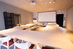 a classroom with tables and chairs and a white screen at ibis Styles Montauban in Montauban