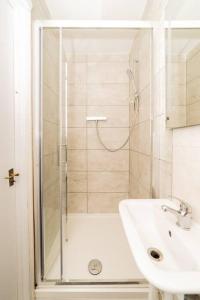 baño blanco con ducha y lavamanos en [Olympia-Museums-Kensington]London Apartment, en Londres