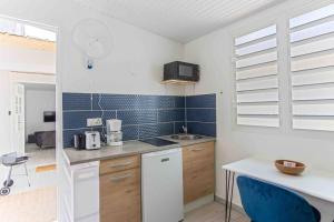 a kitchen with white cabinets and blue tiles on the wall at Le Camélia - Gîte "Terre et Truffes" in Le Lamentin