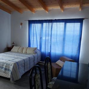 1 dormitorio con cama y cortina azul en Lu-Mar en Comodoro Rivadavia