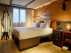 a hotel room with a large bed and a desk at Tribe Paris Saint Ouen in Saint-Ouen