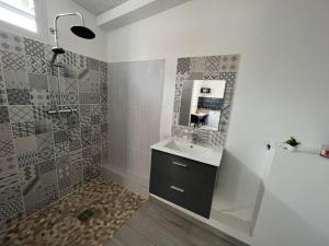 a bathroom with a sink and a shower and a mirror at Le Camélia - Gîte "Terre et Truffes" in Le Lamentin