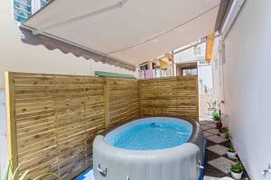 a hot tub in a backyard with a wooden fence at Le Camélia - Gîte "Terre et Truffes" in Le Lamentin
