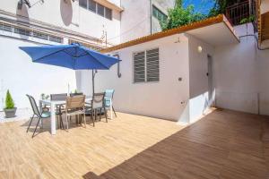 un patio con una mesa y una sombrilla azul en Le Camélia - Gîte "Terre et Truffes" en Le Lamentin