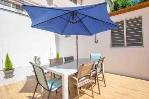 a table with chairs and a blue umbrella at Le Camélia - Gîte "Terre et Truffes" in Le Lamentin