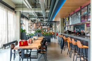 a restaurant with wooden tables and chairs and a bar at Moxy Berlin Airport in Schönefeld